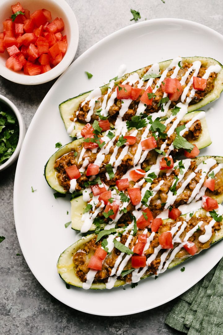 Chicken taco zucchini boats on a plate ready to eat with salsa on the side. 