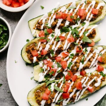 Chicken taco zucchini boats on a plate ready to eat with salsa on the side.