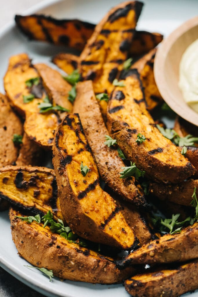 Side view, grilled sweet potatoes on a blue plate, garnished with chopped parsley.