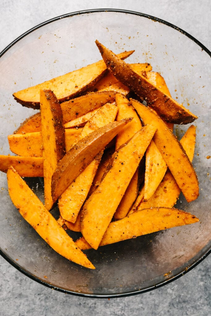 Sweet potatoes cut into wedges and in a bowl, uncooked. 