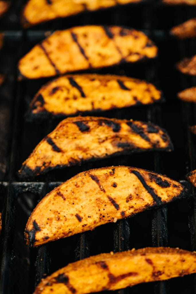 Sweet potato wedges cooking on a grill. 