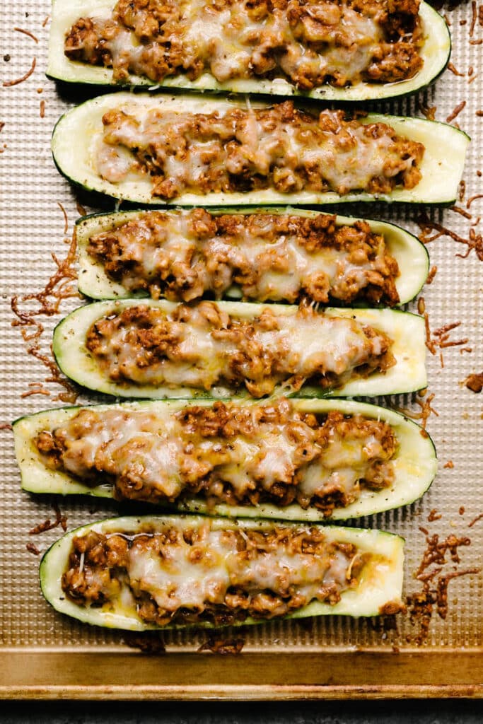 Finished stuffed zucchini boats on a pan with melted cheese. 