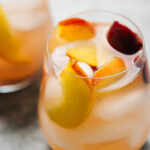 A close up of a wine glass filled with peach sangria.