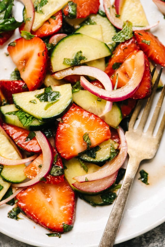Strawberry cucumber salad on a white plate with a fork. 