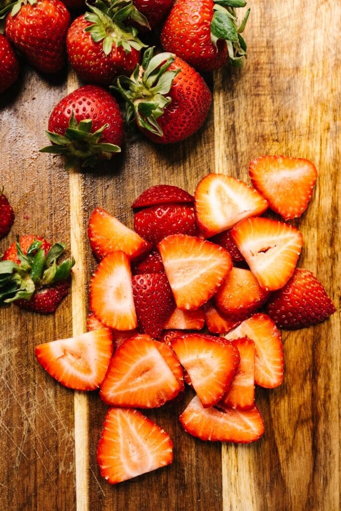 Sliced strawberries on a cutting board. 