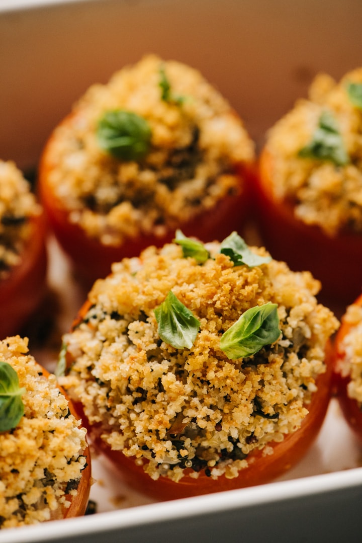 Side view, stuffed tomatoes with quinoa in a casserole dish.