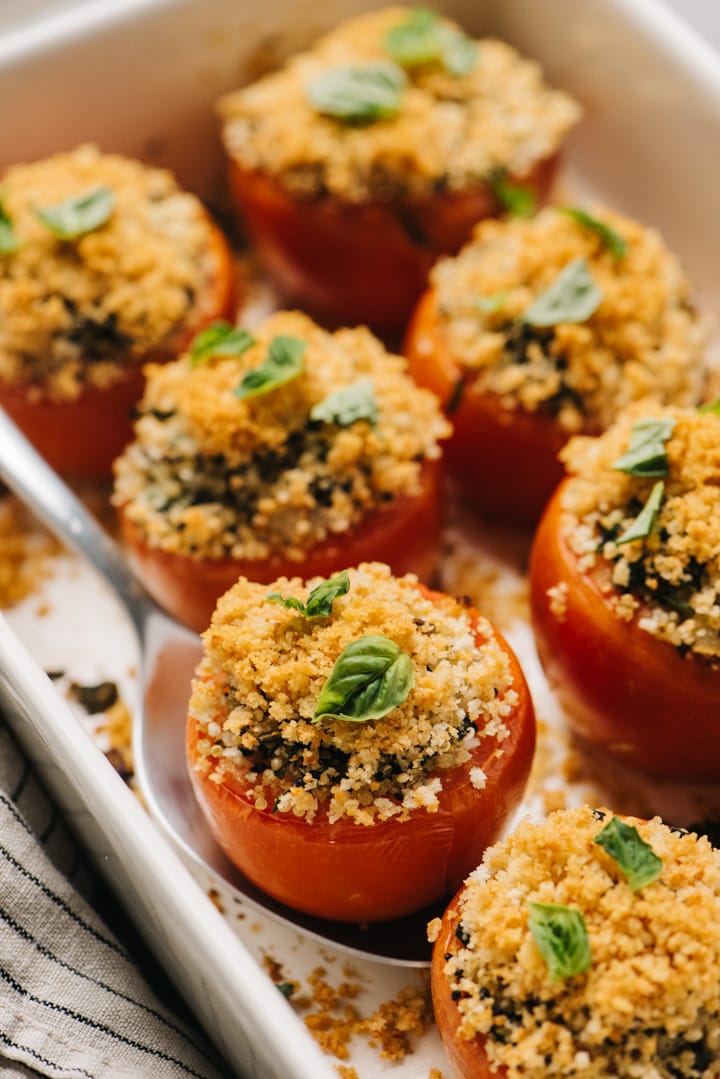Side view, healthy stuffed tomatoes with quinoa in a casserole dish.