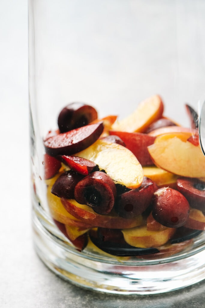 Sliced fruits at the bottom of a glass pitcher. 