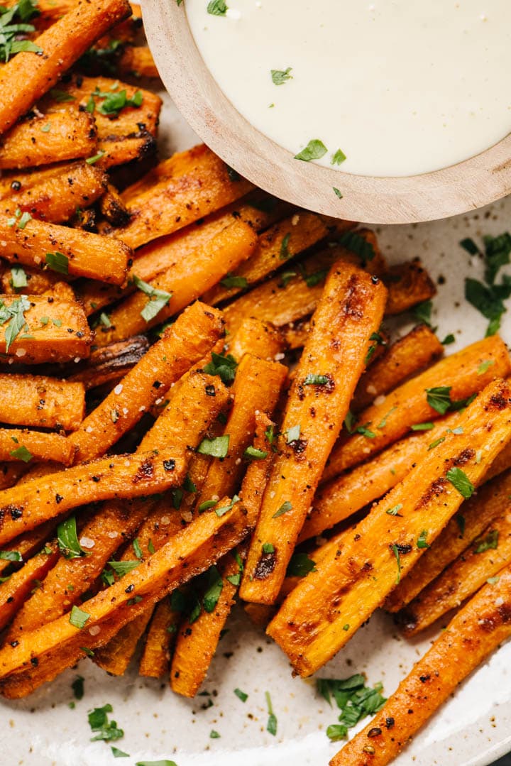 Baked carrot fries on a plate with dipping sauce. 