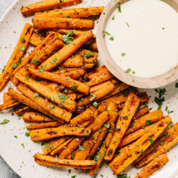 Baked carrot fries on a plate with dipping sauce.