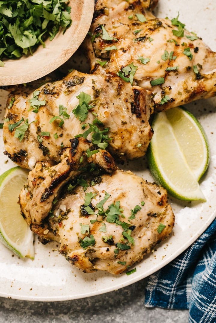 Grilled cilantro lime chicken on a plate with lime wedges. 