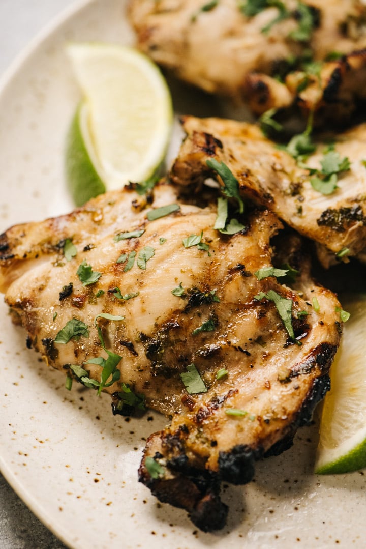Grilled chicken thighs with lime wedges and cilantro. 