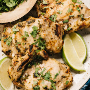 Grilled cilantro lime chicken with lime wedges.