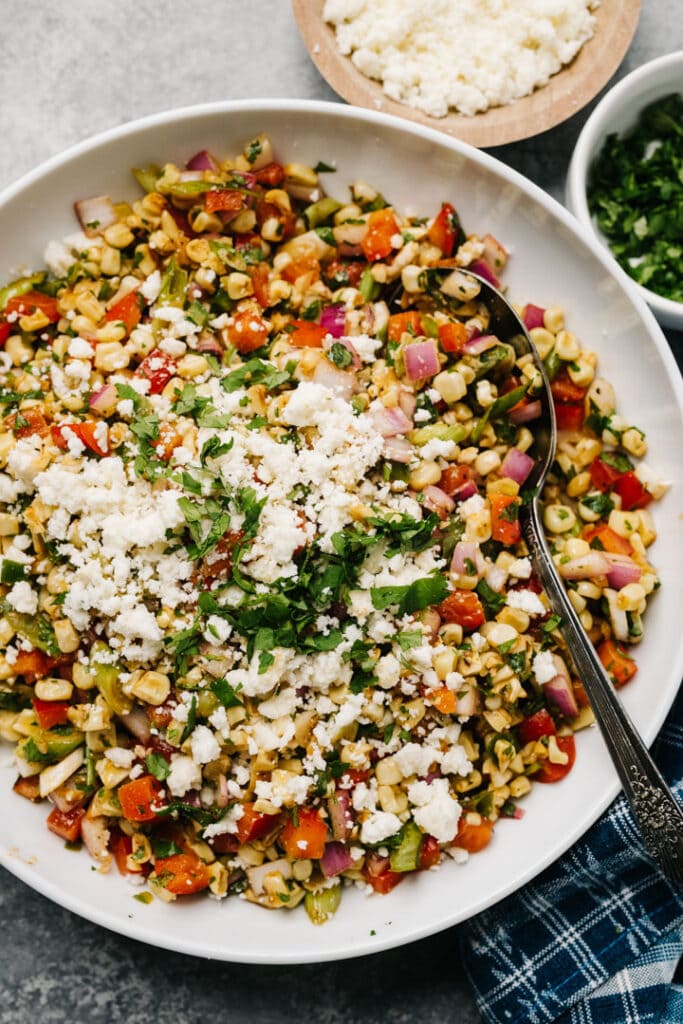 A big bowl of Mexican street corn salad topped with cotija cheese.
