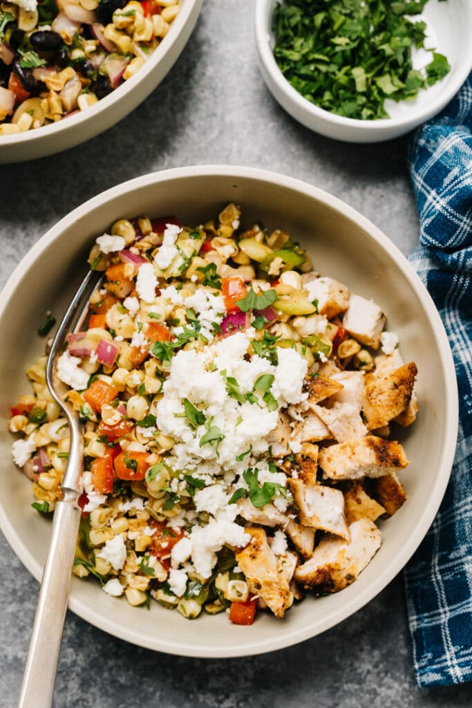 Street corn salad with grilled chicken in a bowl with a silver fork.