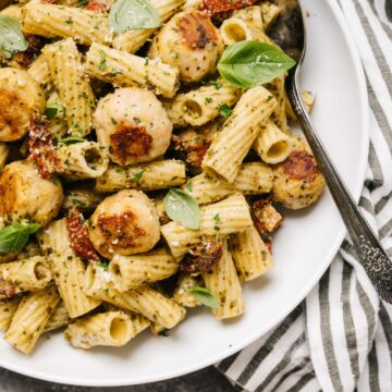 A bowl of pesto pasta with chicken meatballs.