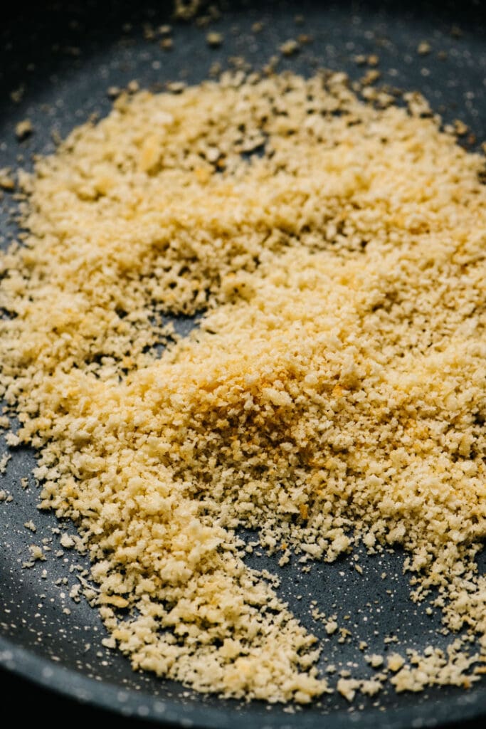 Toasted bread crumbs and parmesan cheese in a skillet.