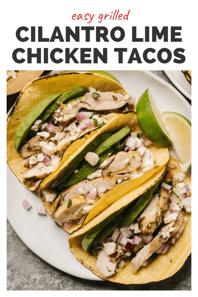 Three cilantro lime chicken tacos on a white plate garnished with sliced avocado, cojita cheese, red onions, and lime wedges; title bar at the top reads "easy grilled cilantro lime chicken tacos".