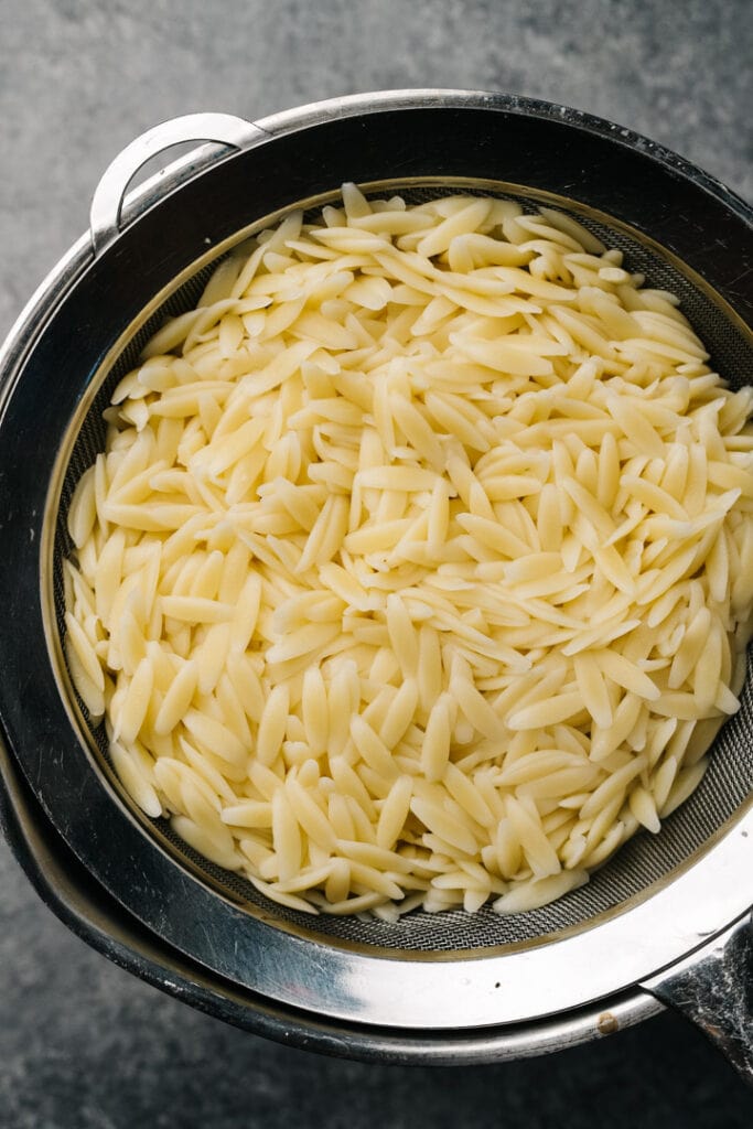 Orzo pasta in a colander to strain.