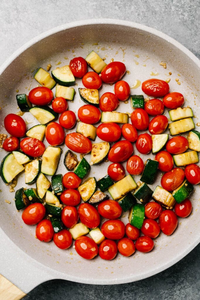 Sautéed zucchini and blistered tomatoes in a skillet.