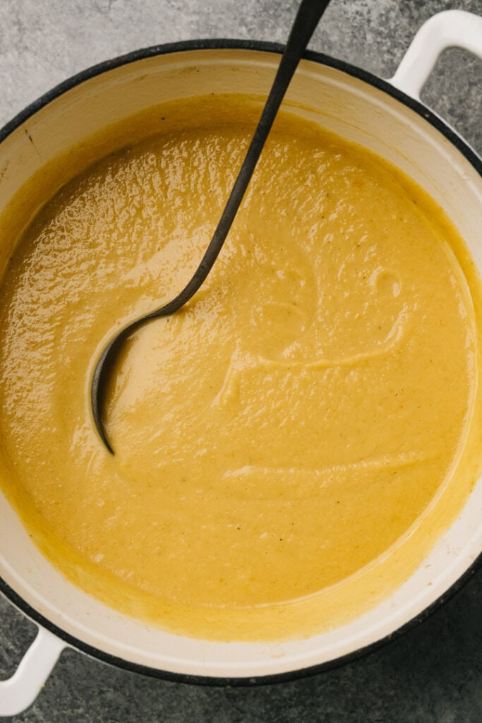 Blended and ready to eat acorn squash soup in a pot with a large serving spoon. 