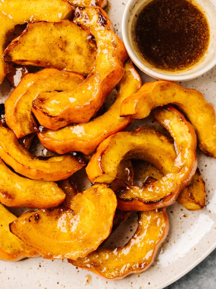 Acorn squash slices on a plate with a small bowl of dipping sauce.