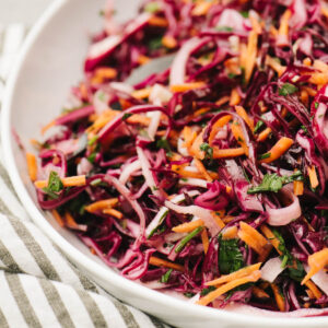 Red cabbage with carrots coleslaw on a white plate.