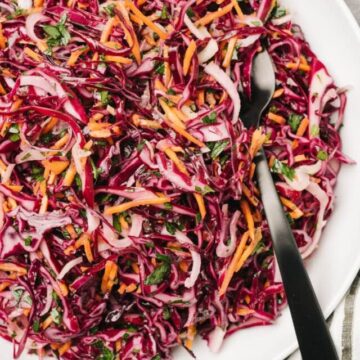 Red cabbage coleslaw on a white plate with a fork.