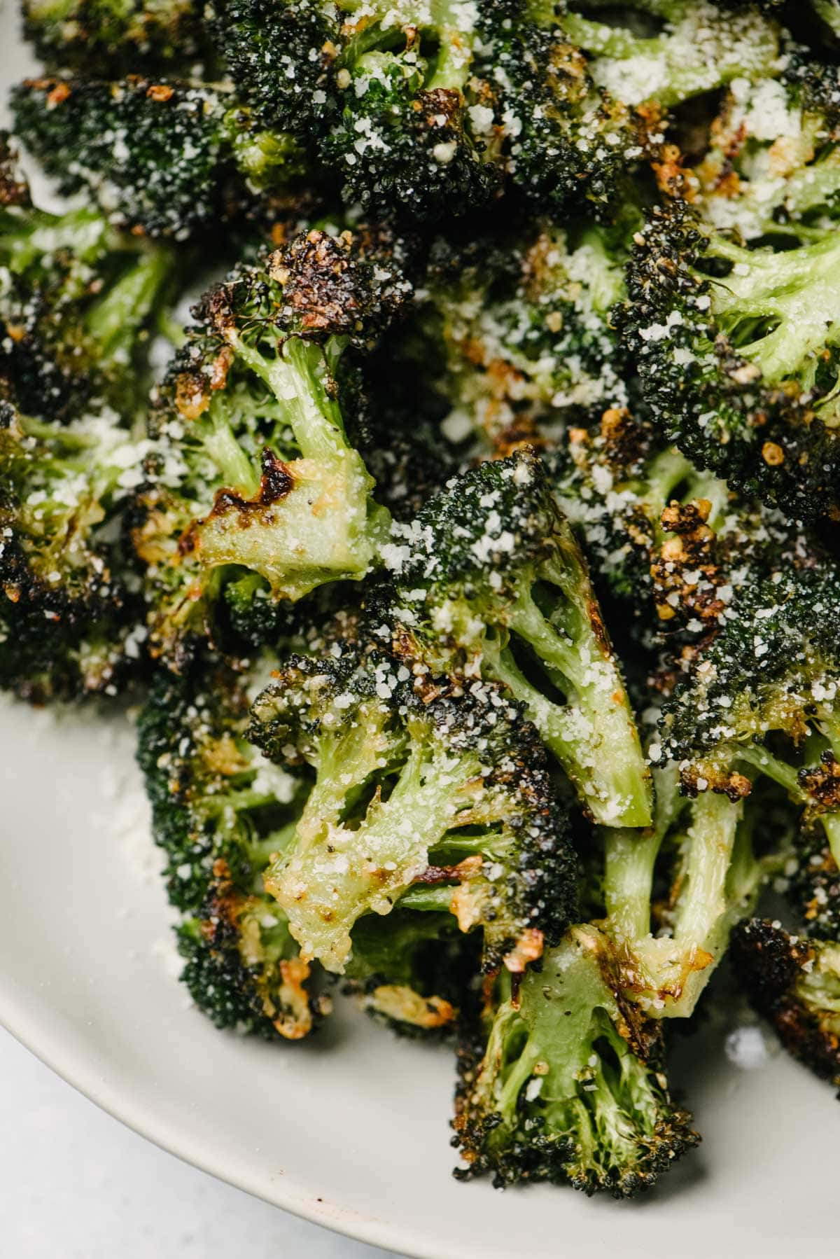 Roasted broccoli with parmesan and garlic in a white serving bowl.