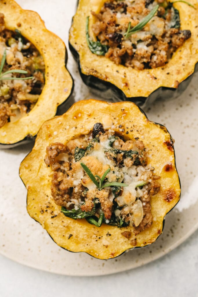 Three acorn squash halves stuffed with sausage, vegetables and fresh herbs and topped with parmesan cheese.