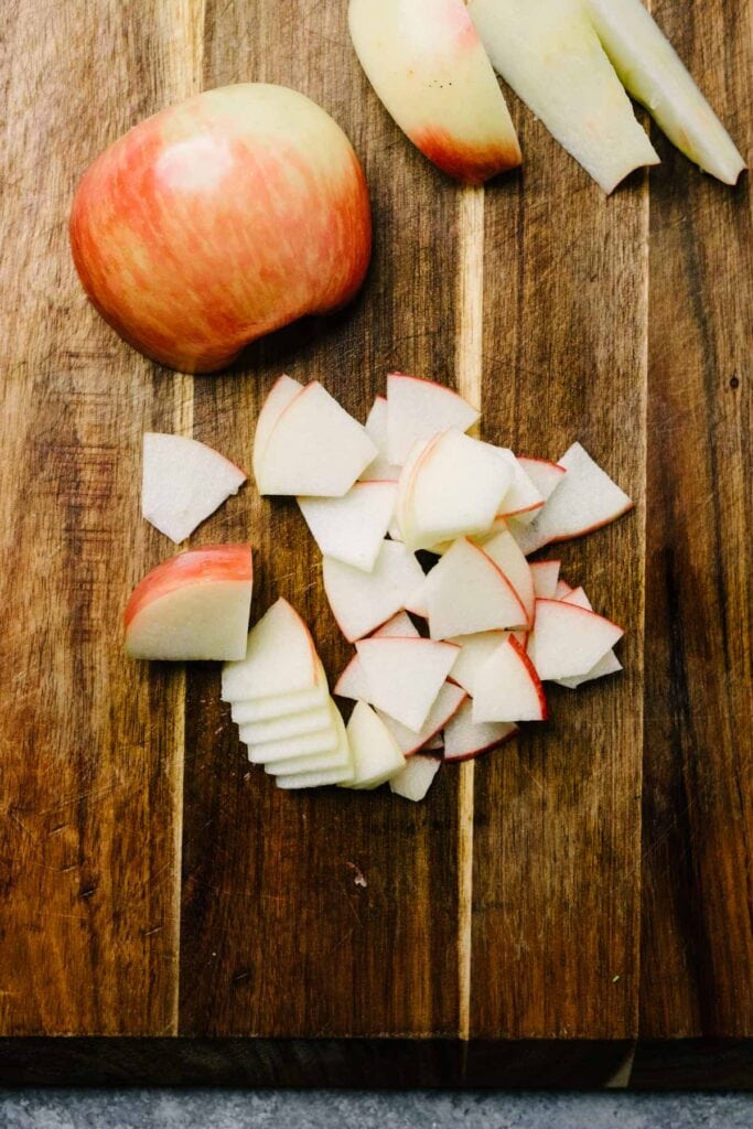 Thinly sliced apples on a wood cutting board.