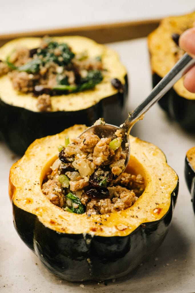 Side view, filling roasted acorn squash halves with sausage stuffing.
