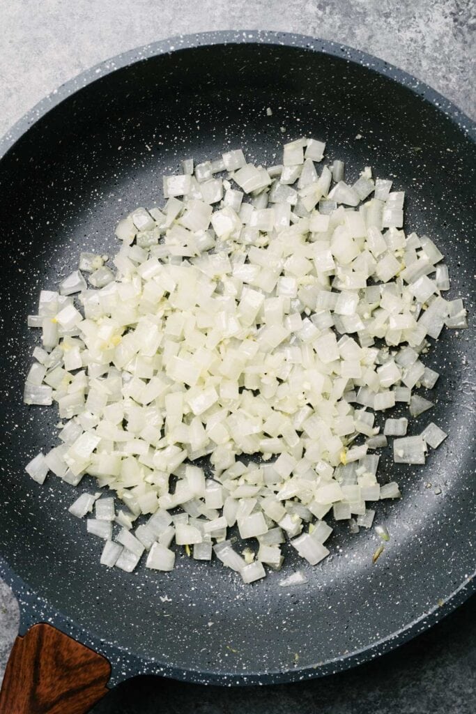 Sautéed onions and garlic in a dark grey skillet.