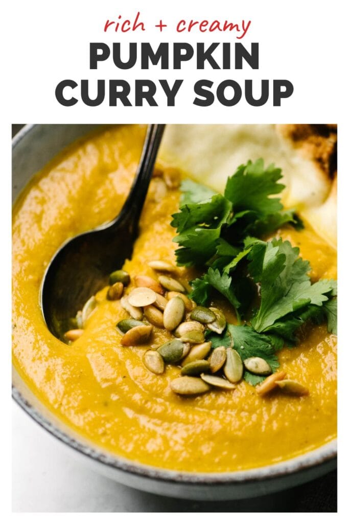 Side view, a spoon tucked into a bowl of pumpkin soup garnished with peptias and fresh cilantro with a title bar at the top that reads "rich and creamy pumpkin curry soup".