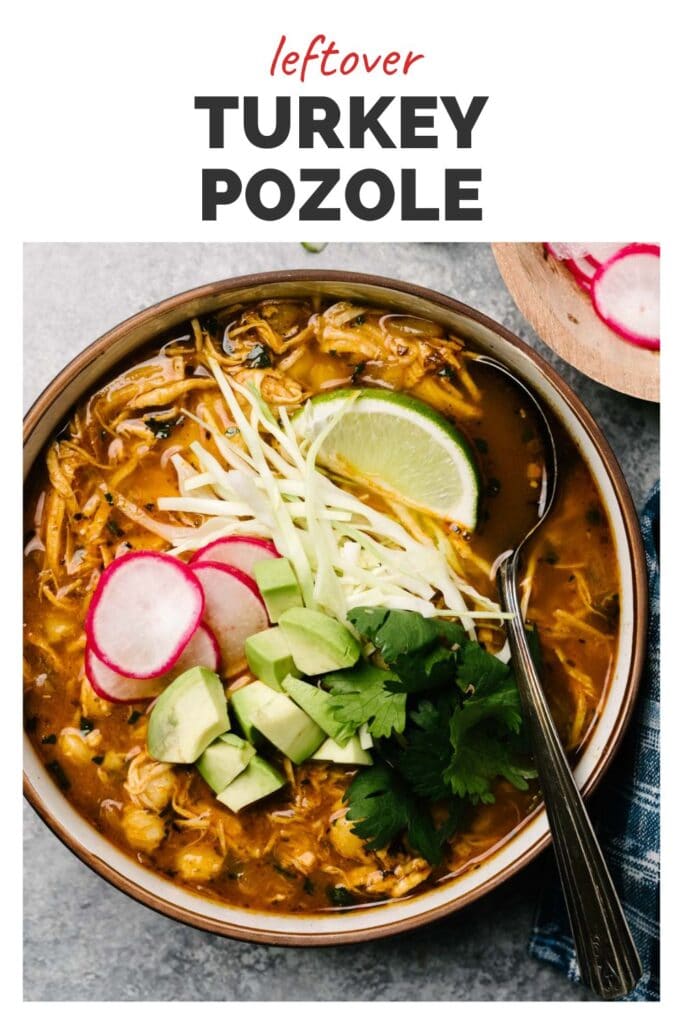 Top view of a bowl of turkey pazole topped with cabbage, cilantro, avocado, lime wedges, and radish slices with a top banner that reads leftover turkey pozole.