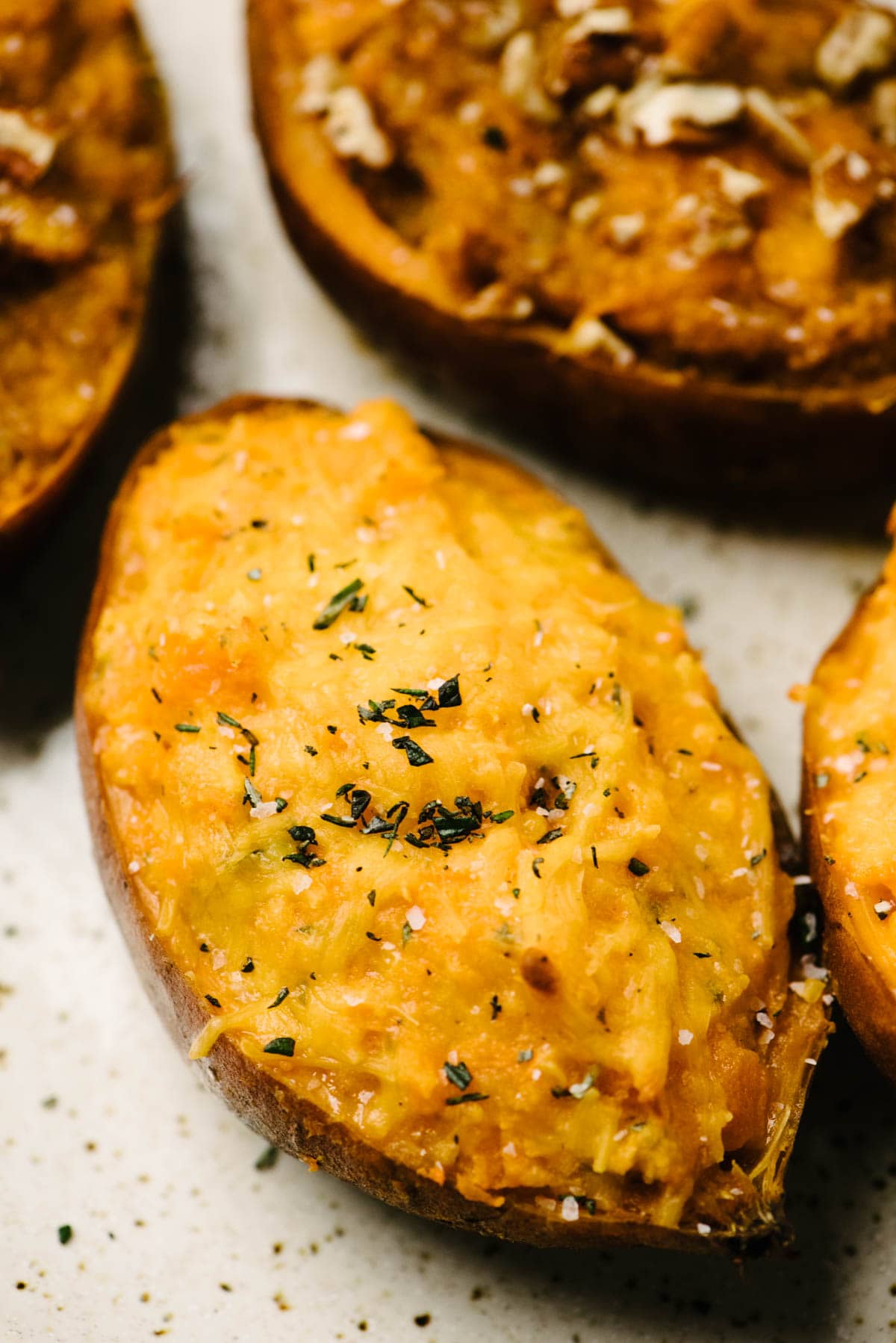Twice baked sweet potatoes on a baking sheet, finished with melted cheese and spices.