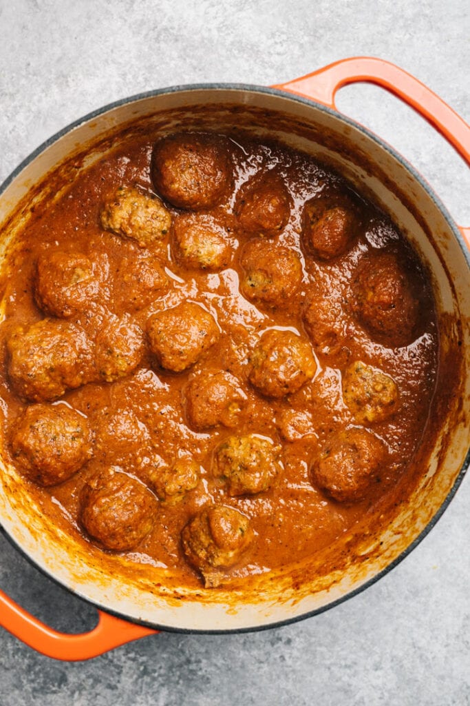 Healthy meatballs simmered in a pot of marinara sauce.