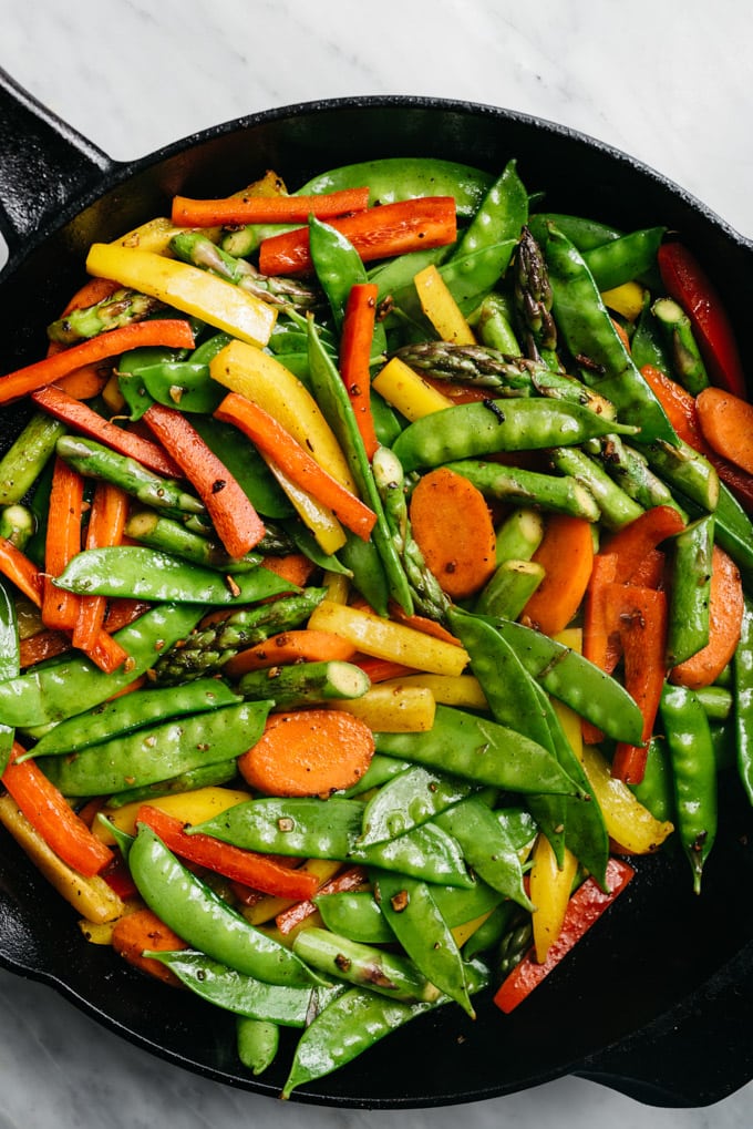 Stir fried vegetables - asparagus, carrots, bell peppers, and snow peas - in a cast iron skillet.