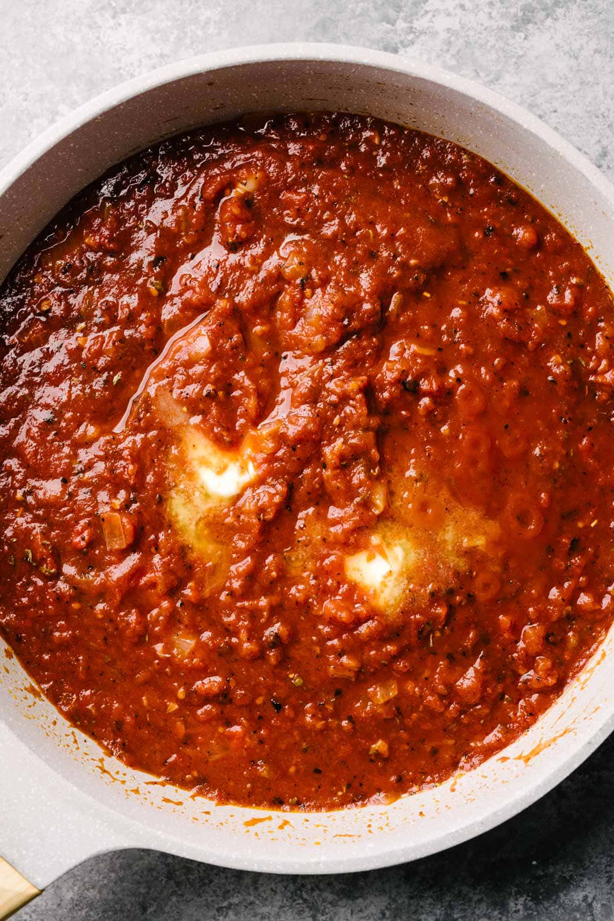 Healthy marinara sauce in a skillet with melting ghee, before simmering.