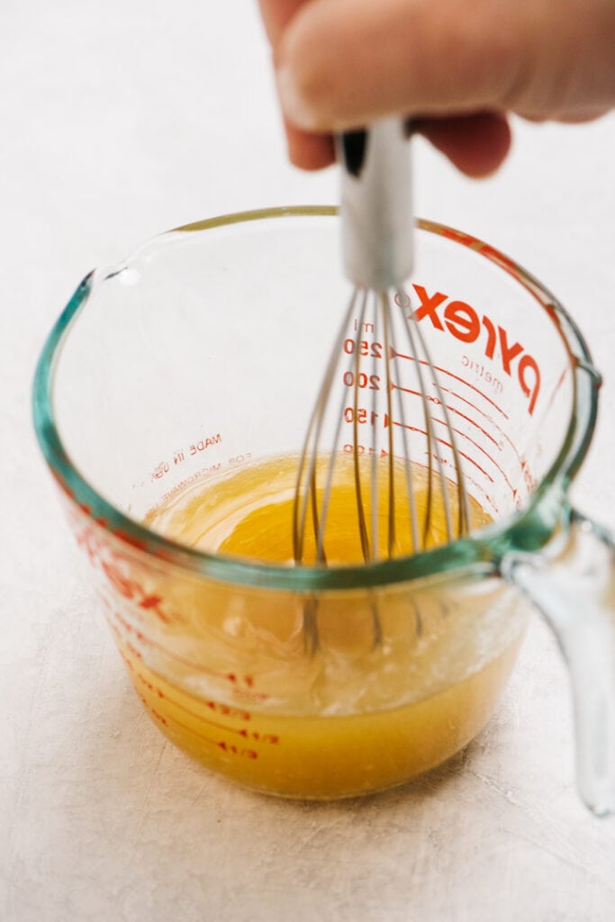 Whisking citrus dressing in a pyrex mixing cup.
