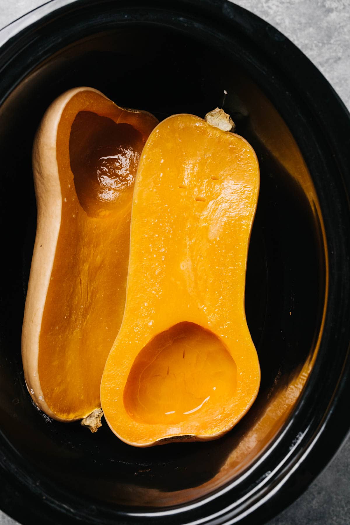 Soft and tender butternut squash halves in a slow cooker.