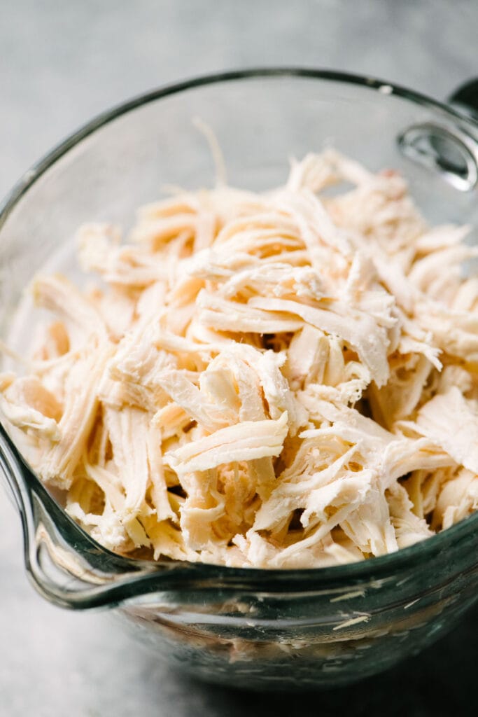 Side view, shredded chicken in a large glass bowl.