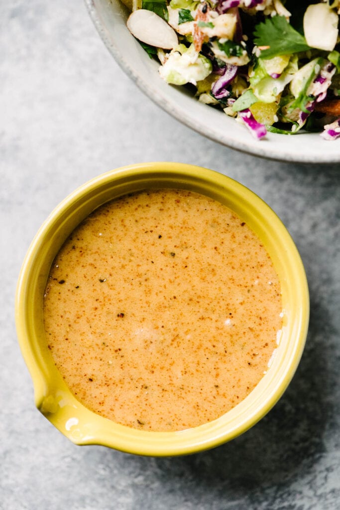 Asian almond butter dressing for chicken salad in a small yellow spouted bowl.