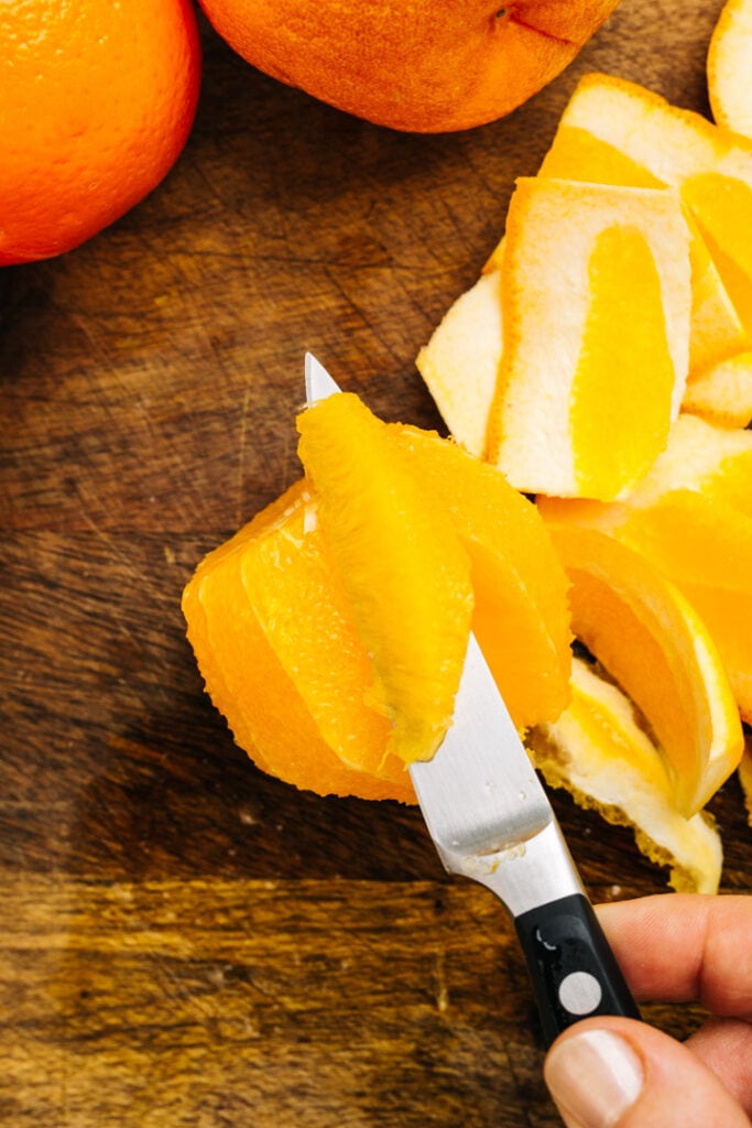 A citrus supreme (segment) on a paring knife.