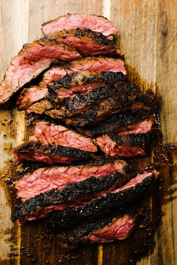 Thin slices of fajita steak on a cutting board.