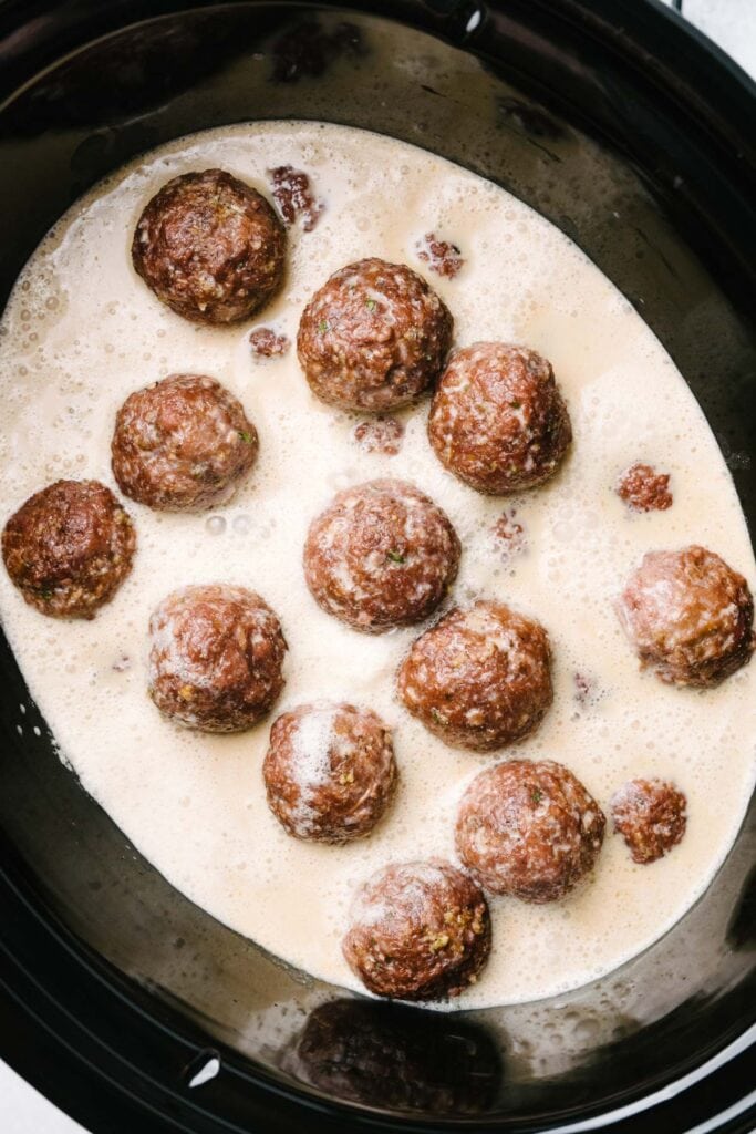 Browned Swedish meatballs and sauce in a crockpot before slow cooking.