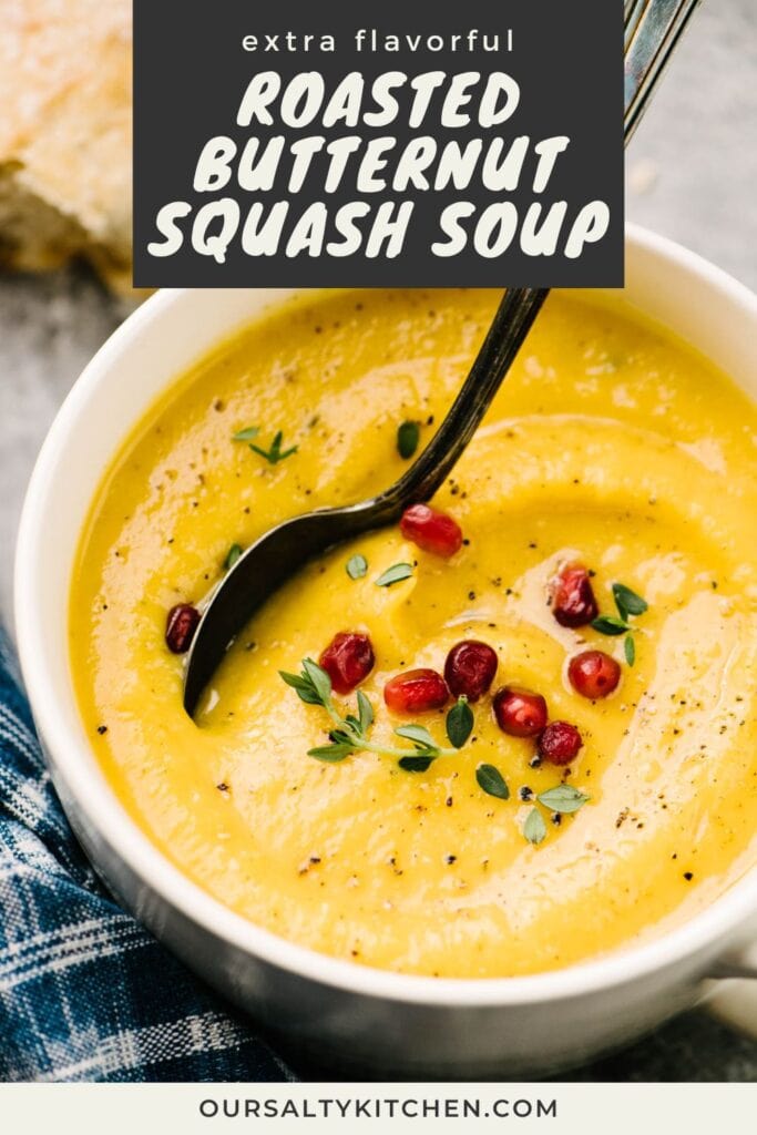Side view, a soup spoon tucked into a bowl of creamy roasted butternut squash soup garnished with fresh thyme and pomegranate seeds; title bar at the top reads "extra flavorful roasted butternut squash soup".