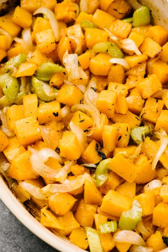 Roasted butternut squash, onions, and celery in a casserole dish.