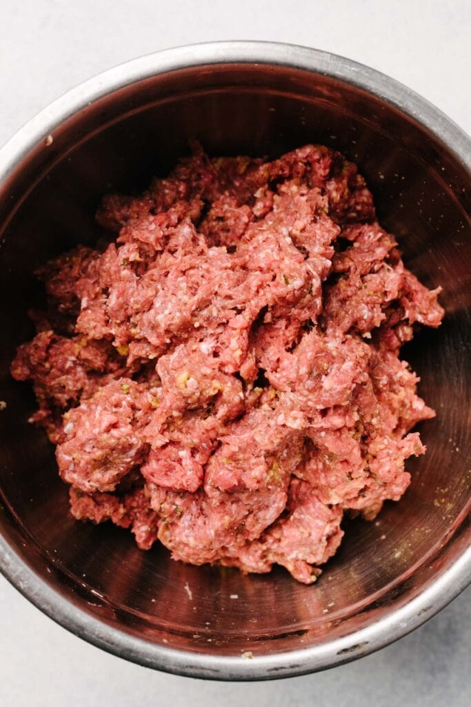 Swedish meatball ingredients combined in a large metal mixing bowl.