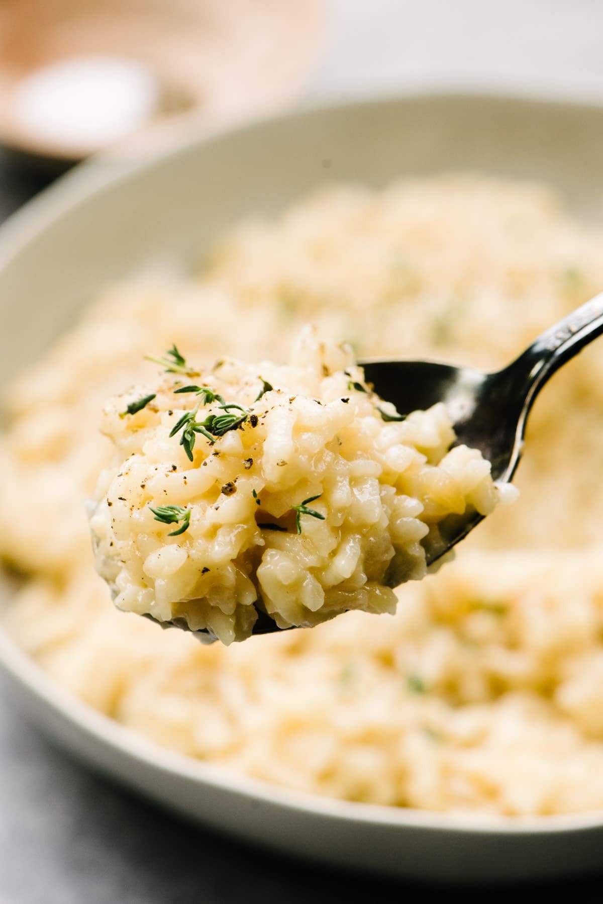 A spoonful of risotto hovering over a bowl, showing the rich and creamy texture.